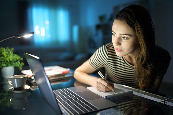 Focused woman working on a laptop at night, representing USTax101's online tax services for nonresidents and expats.