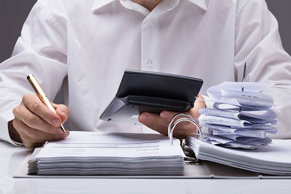 Person calculating finances and reviewing documents with a stack of receipts, representing USTax101's tax preparation services for nonresidents and businesses.